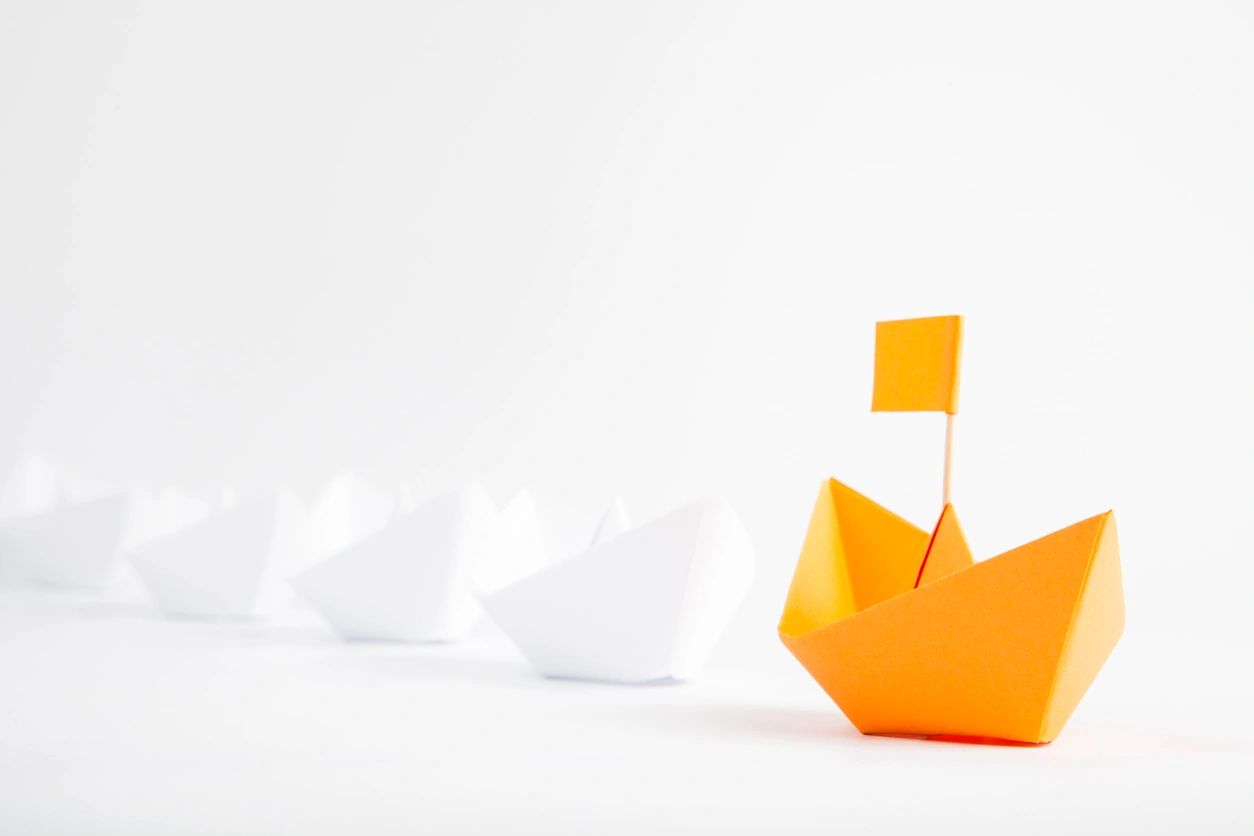 Leadership illustration — orange paper boat standing out